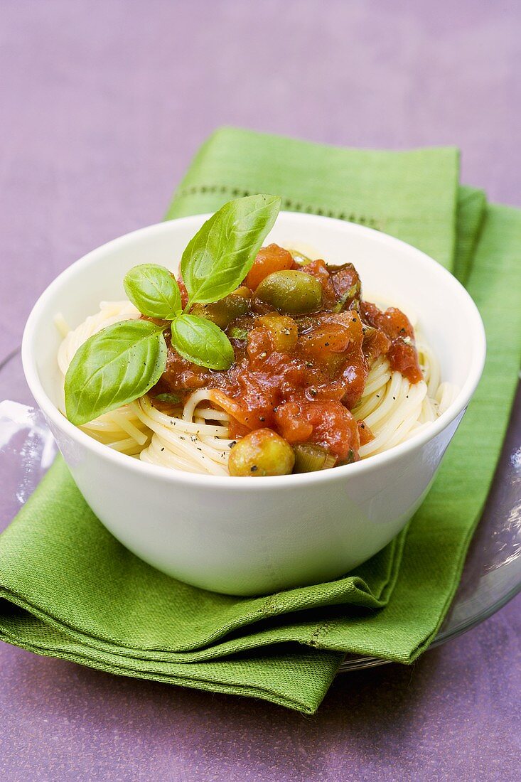 Spaghetti with tomato sauce, green olives and basil