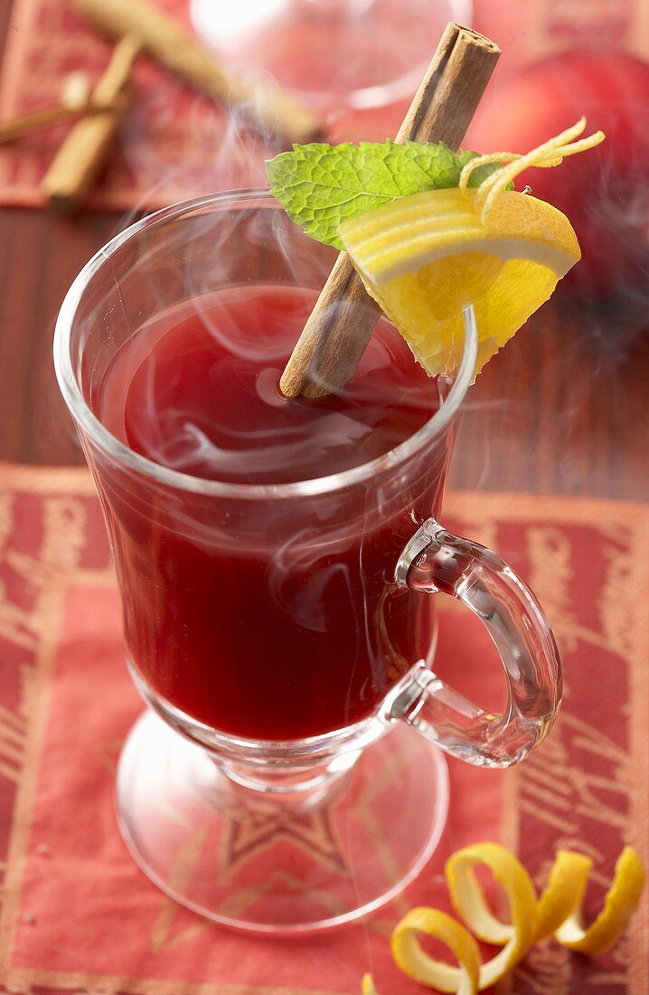 A glass of punch with cinnamon stick and lemon