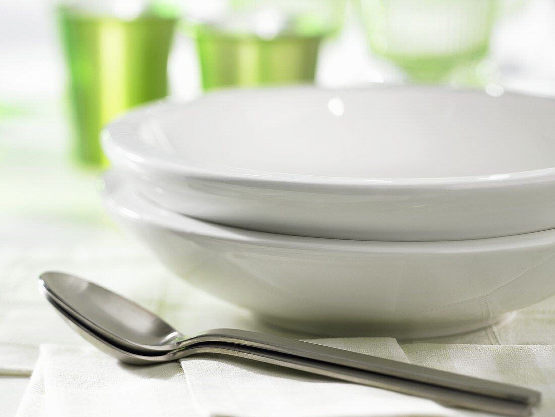 Two white soup plates with spoons