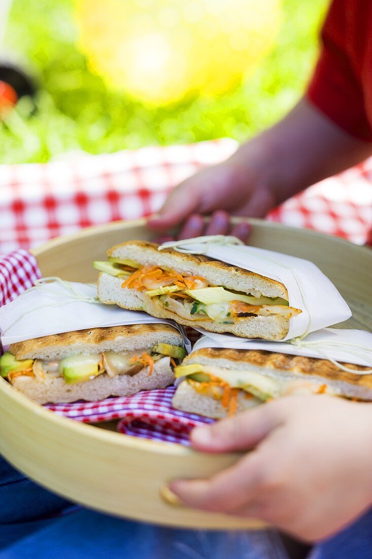 Child's hands holding tray of focaccia sandwiches