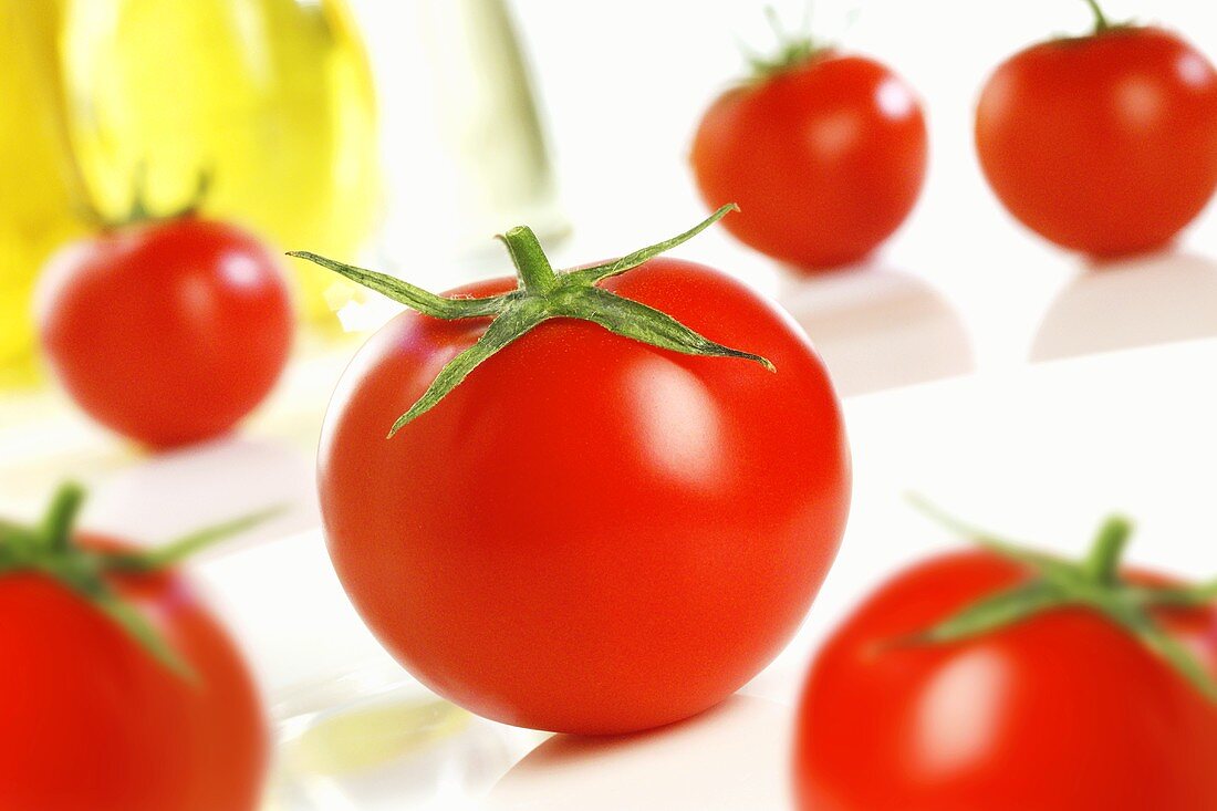 Tomaten mit Ölflaschen im Hintergrund