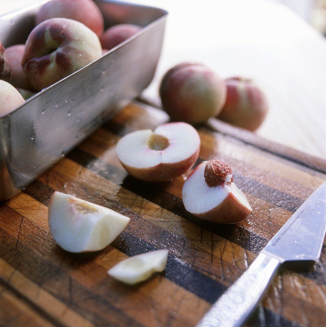 Peaches, whole and cut into pieces, on a wooden board