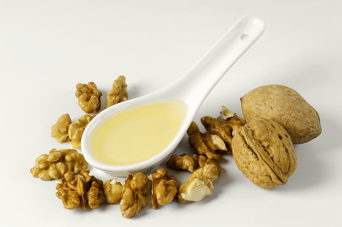 Walnut oil on a spoon with shelled walnuts