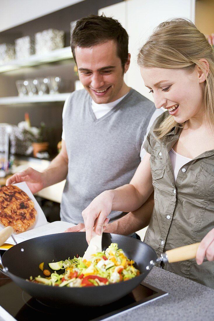 Young couple cooking vegetables in wok