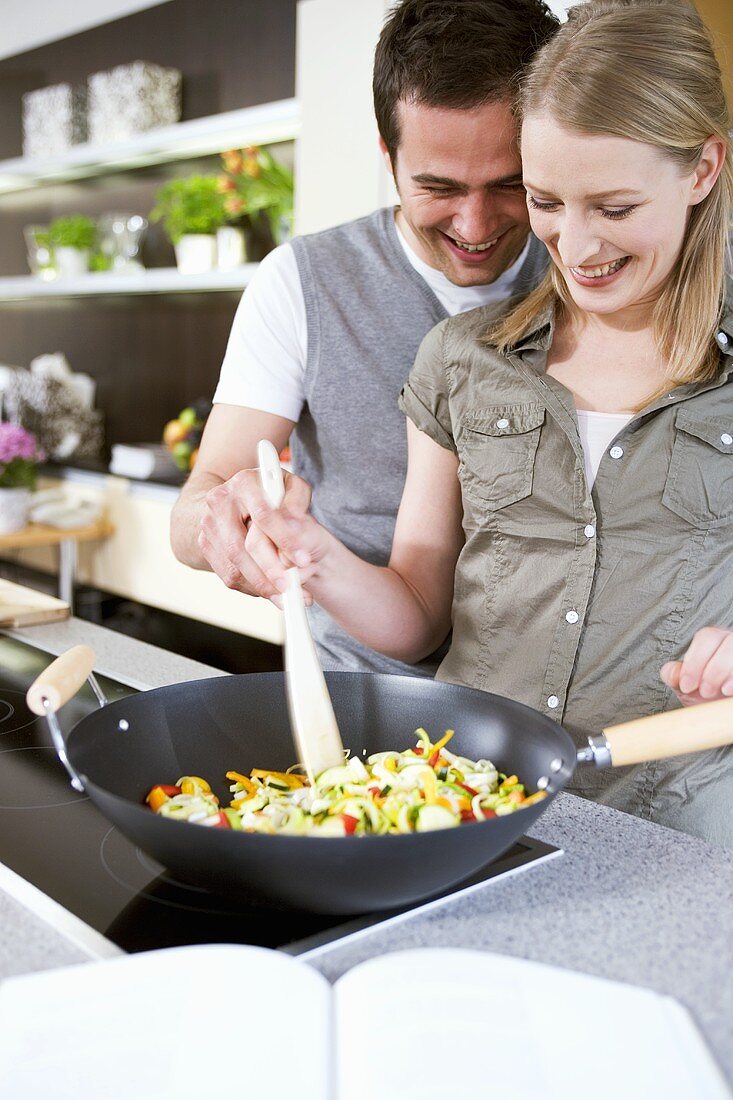 Mann und Frau wenden Gemüse im Wok