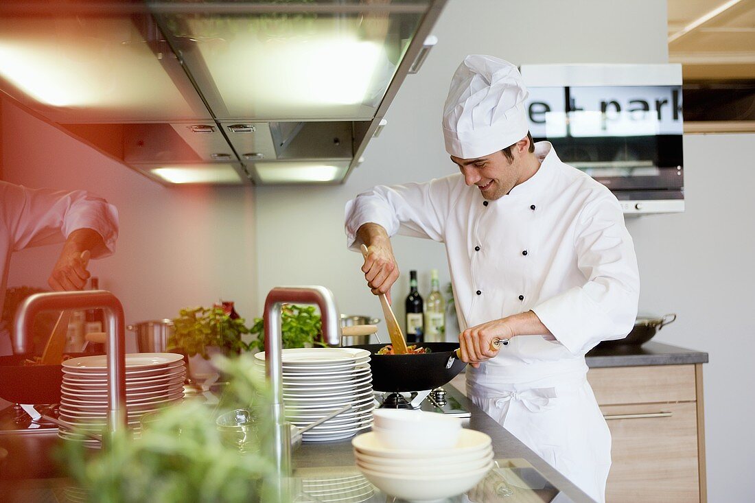 Young chef cooking vegetables in wok