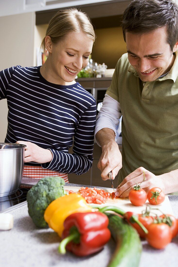 Young couple chopping tomatoes