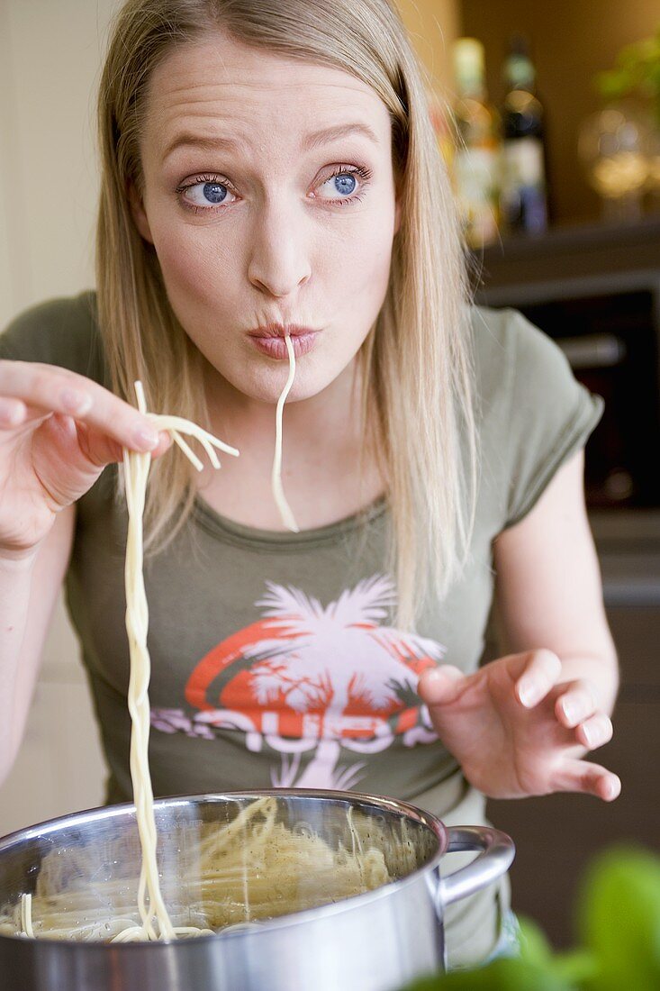 Junge Frau probiert gekochte Spaghetti