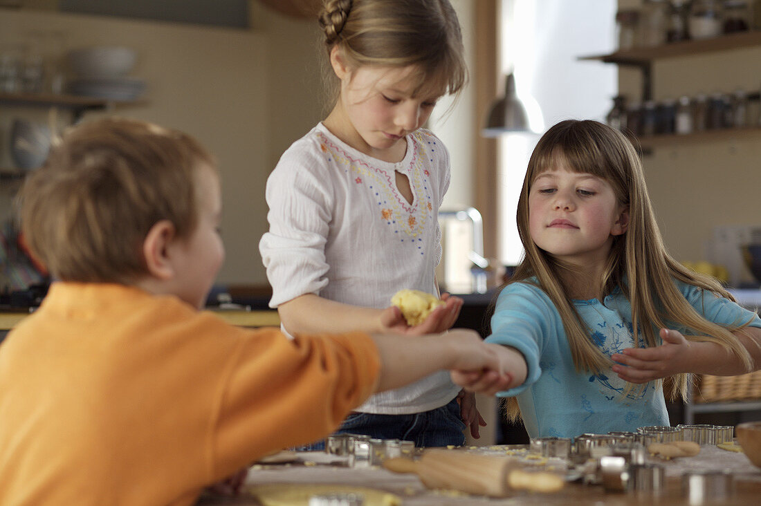 Three children baking biscuits