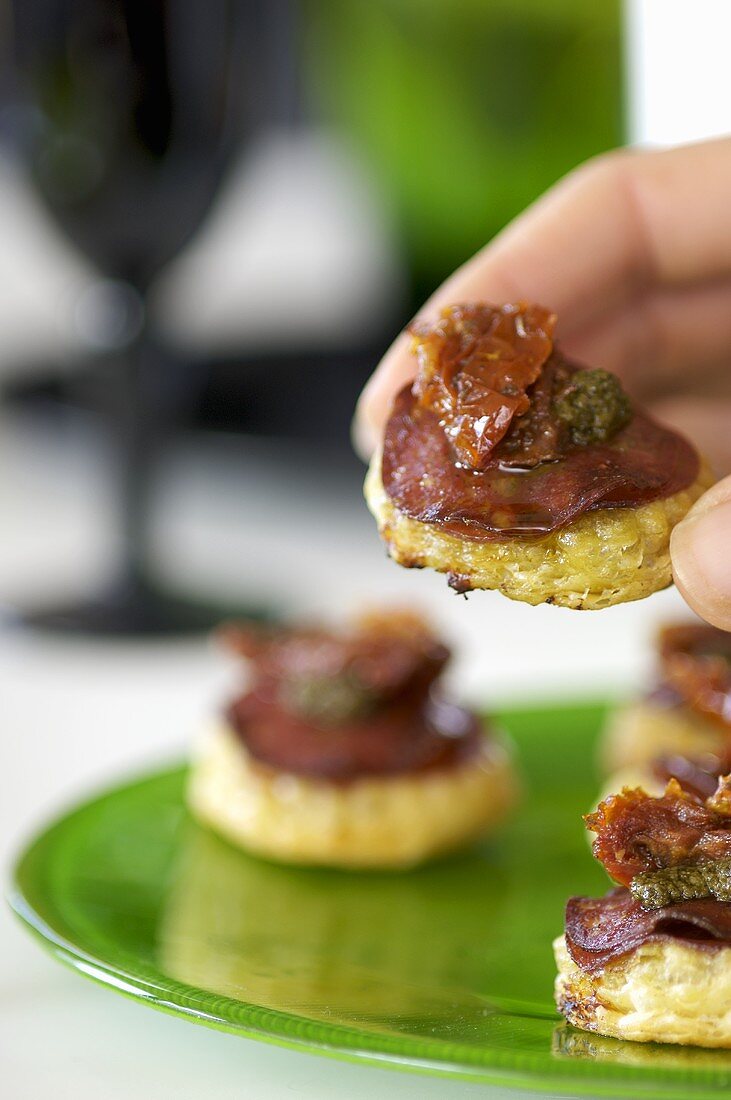 Hand hält ein Salami-Tart