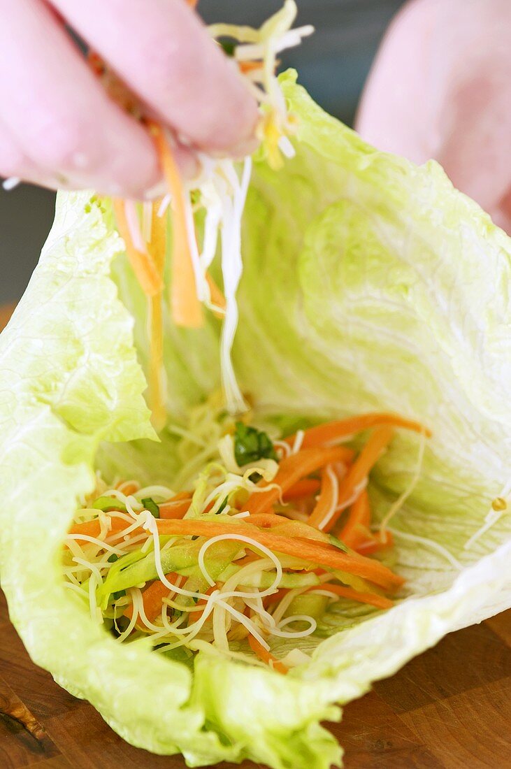 Filling a lettuce leaf with vegetables