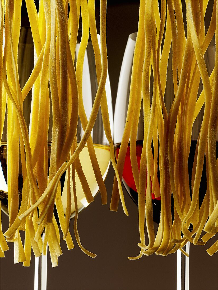 Two glasses of wine behind hanging pasta