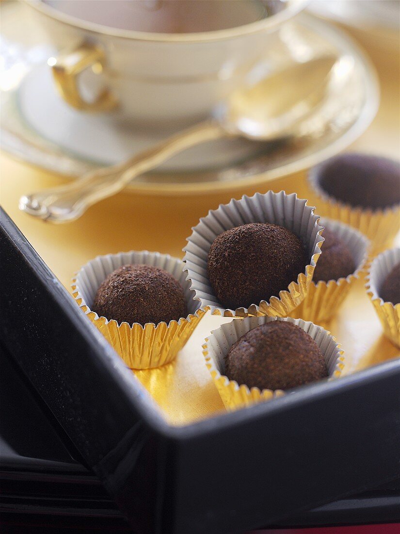 Chocolate truffles beside a teacup and saucer
