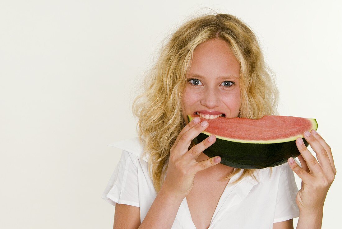Blonde Frau beisst in eine Melonenspalte