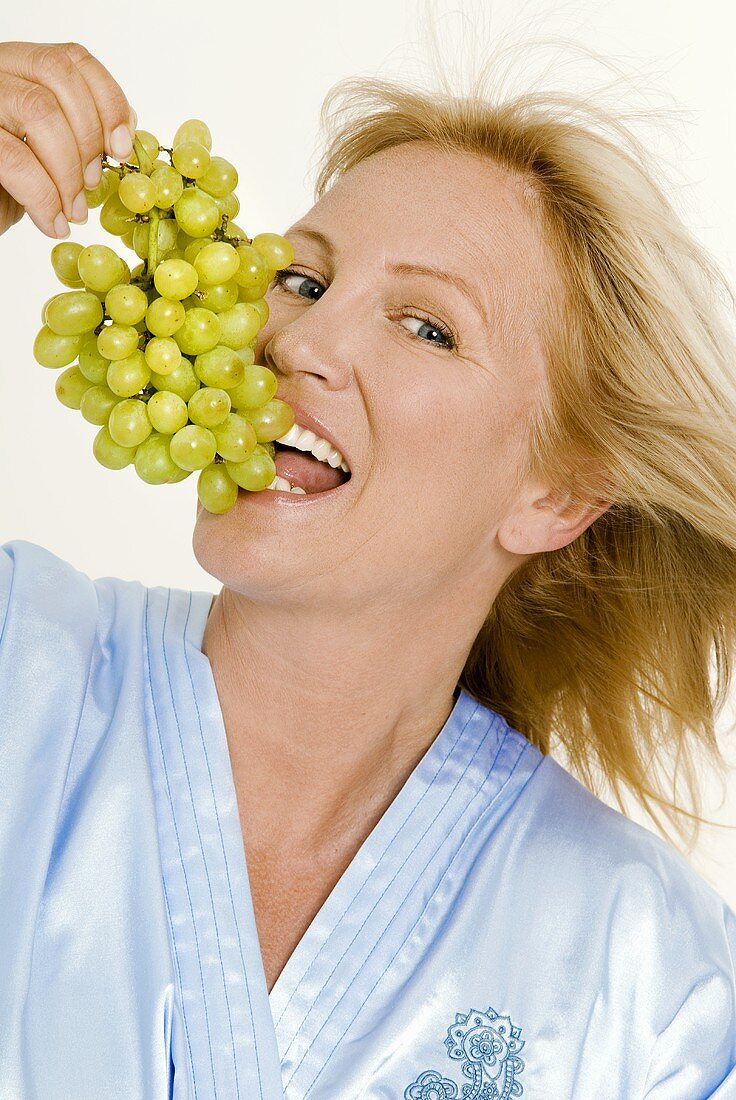 Blonde Frau isst Weintrauben
