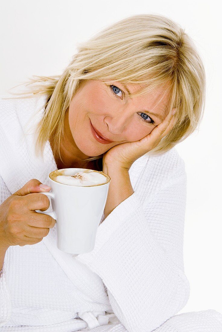Blond woman holding a cup of cappuccino in her hand