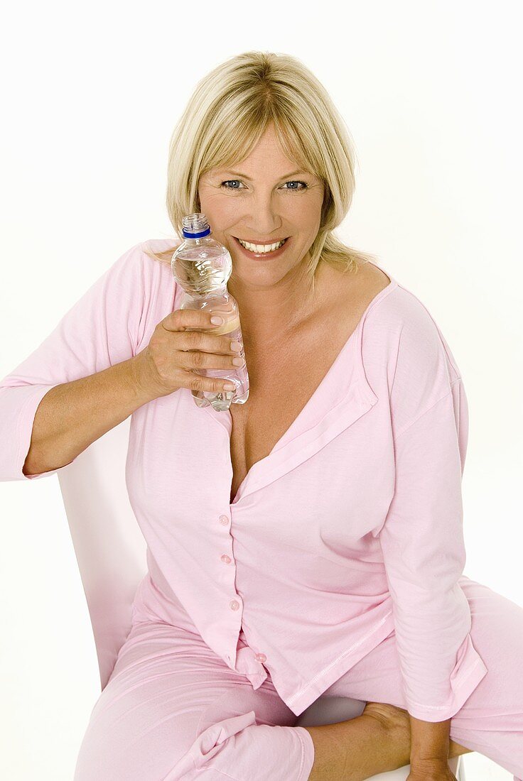 Woman sitting on a chair with a bottle of mineral water
