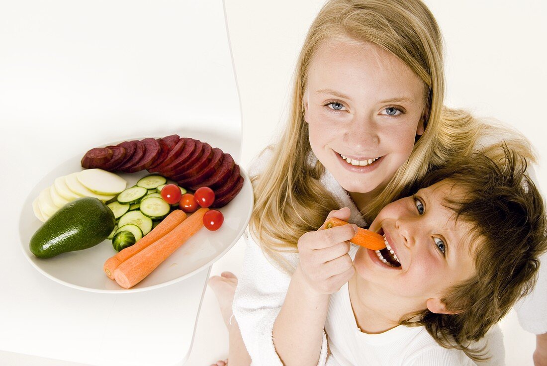Zwei Kinder knabbern frisches Gemüse