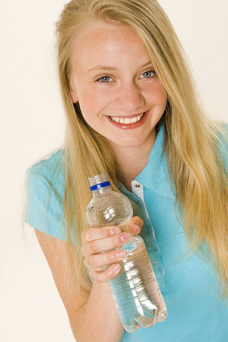 Blondes Mädchen hält eine Mineralwasserflasche in der Hand