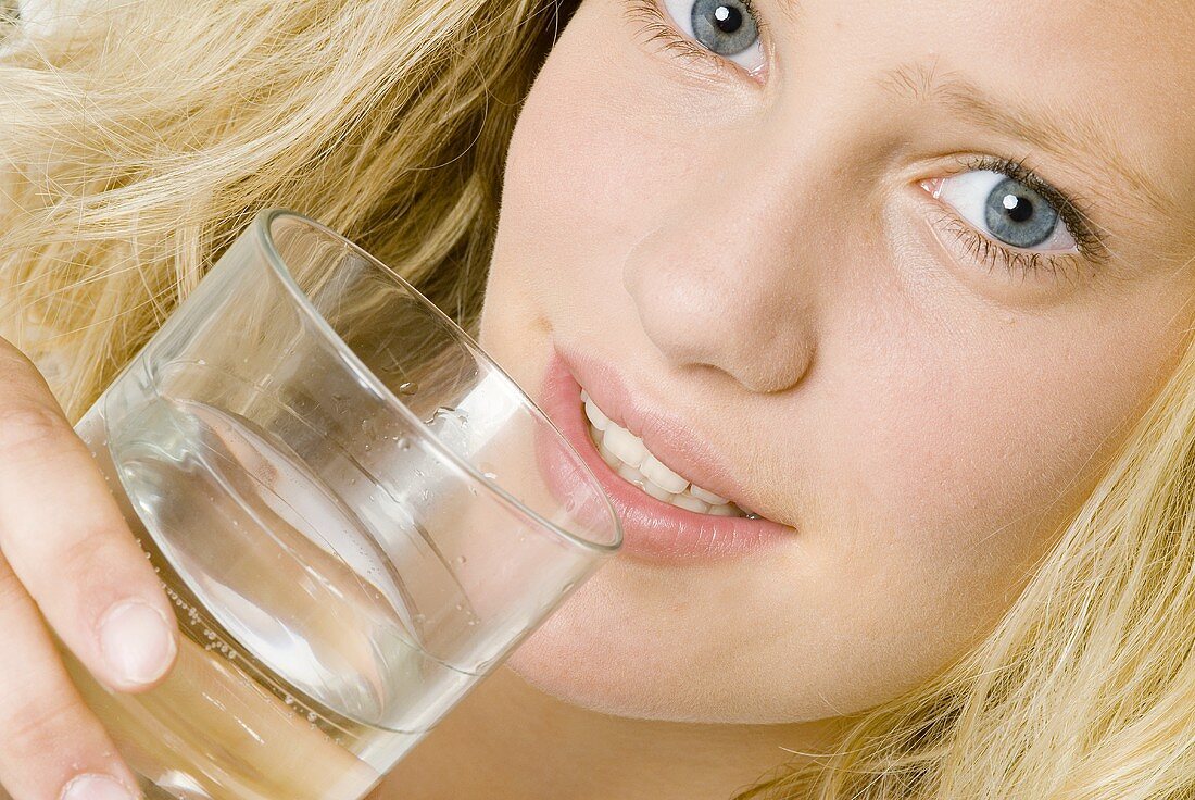 Junge Frau hält ein Glas Mineralwasser