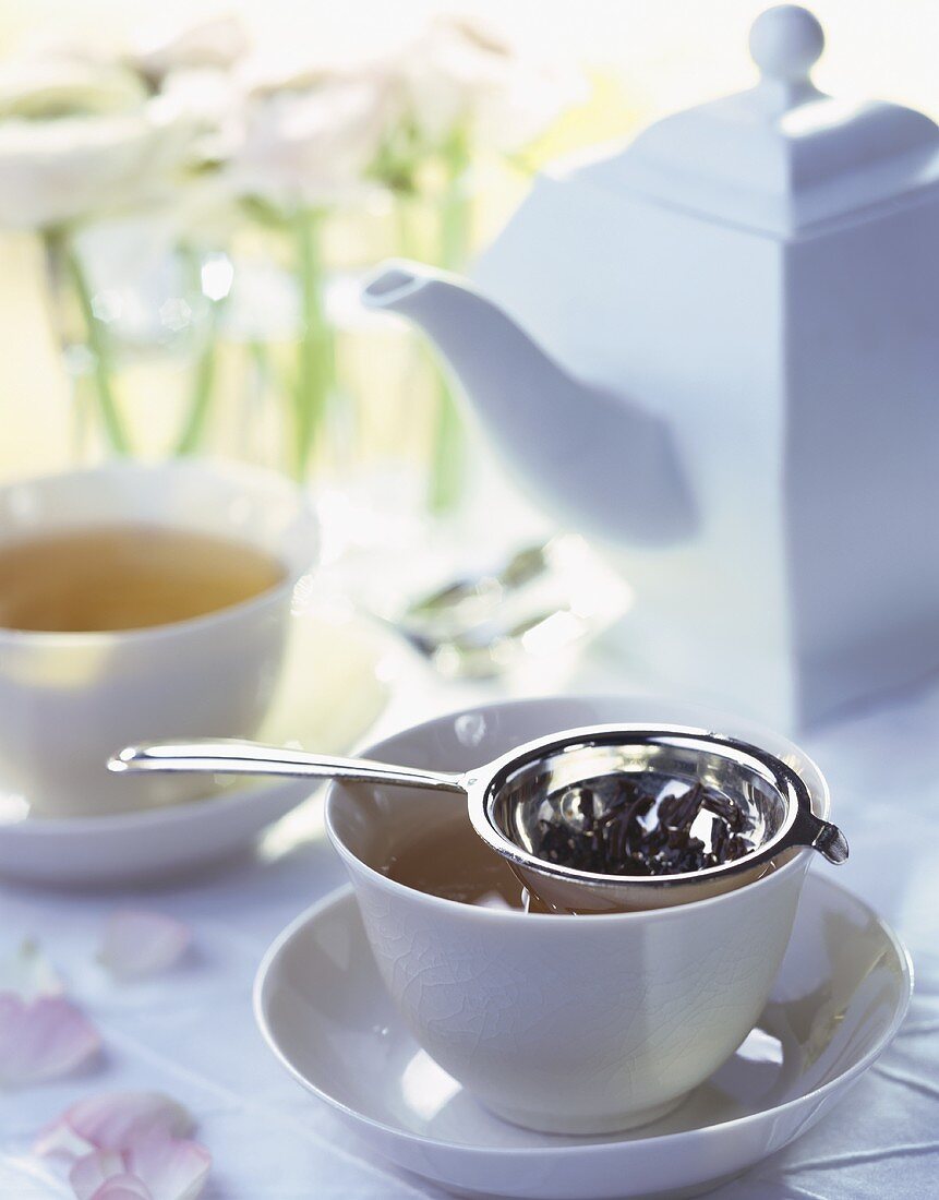 Teetasse mit aufgebrühtem Tee und Teesieb