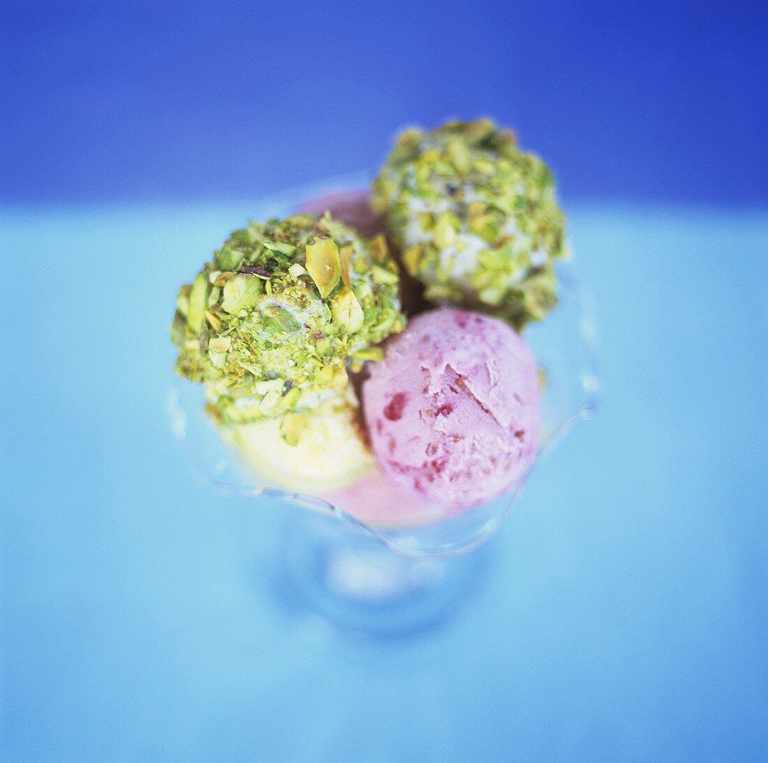 Scoops of pistachio, raspberry & peach ice cream in glass bowl