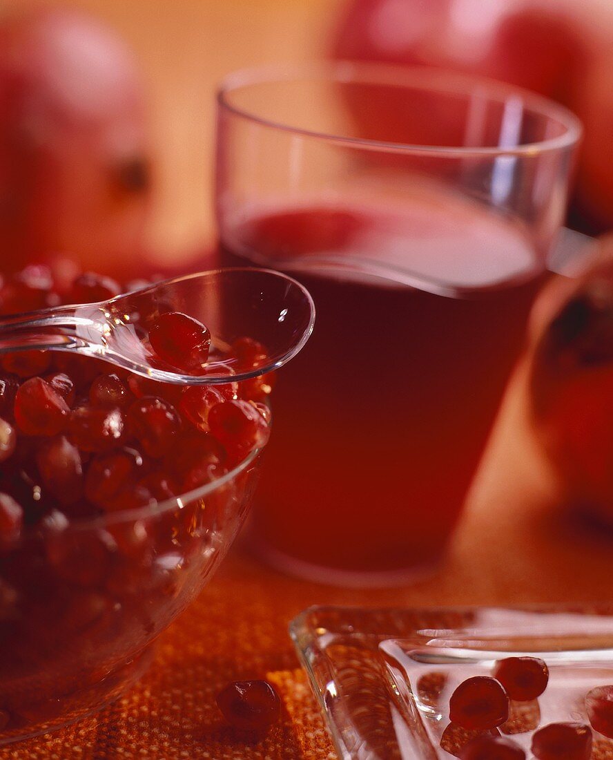 A glass of pomegranate juice, pomegranate seeds in foreground