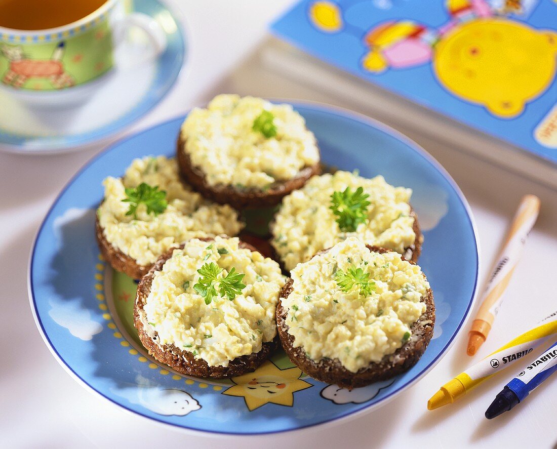 Scrambled egg with herbs on pumpernickel rounds