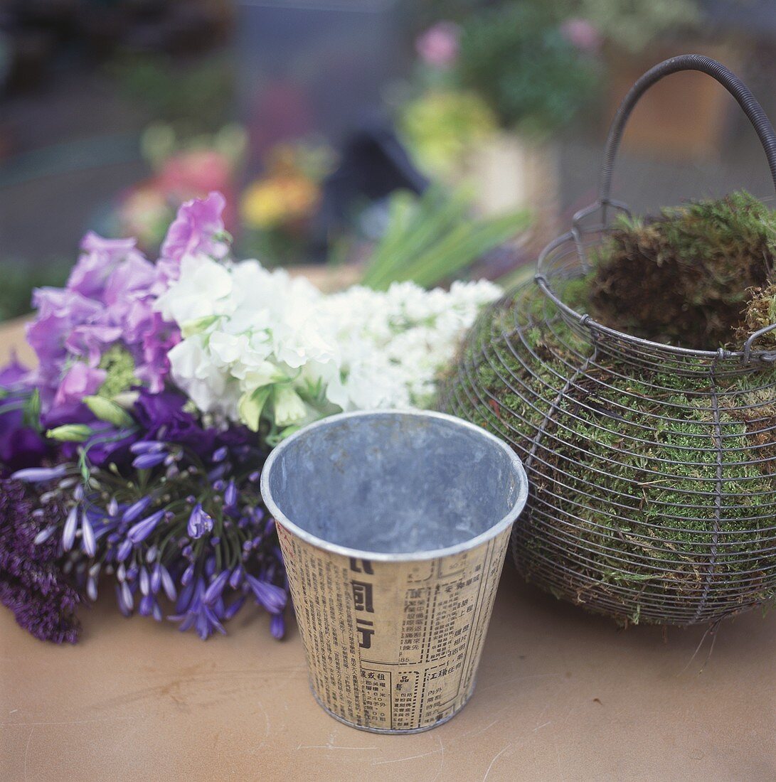 Basket of moss, metal cache-pot and flowers