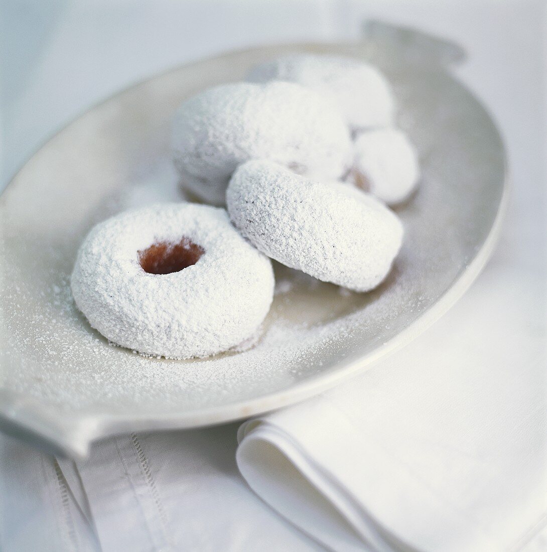 Doughnuts with icing sugar on white platter