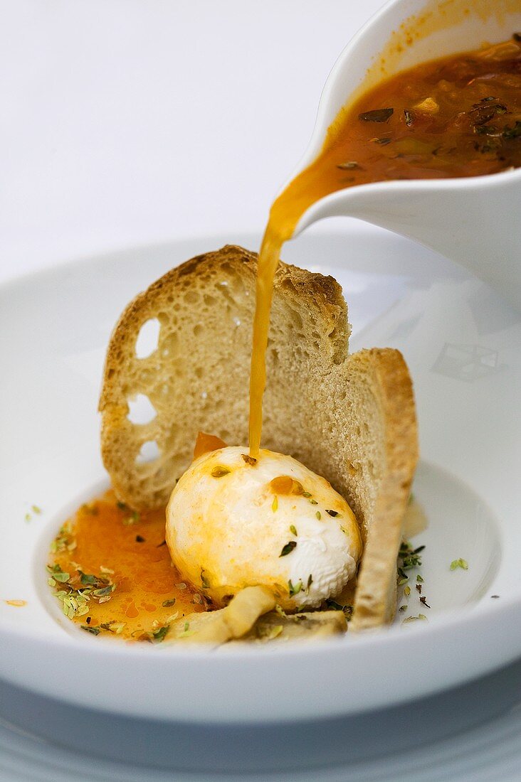 Pouring tomato soup over poached egg