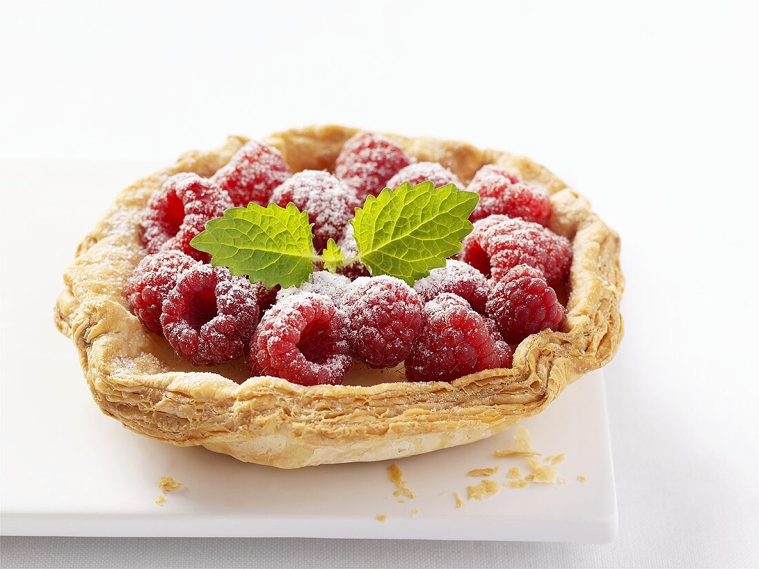 Raspberry tart with puff pastry case and icing sugar