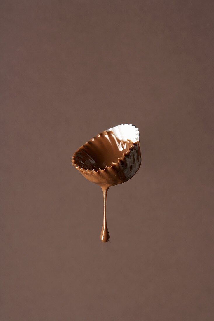 Flüssige Schokolade tropft von einem Papierförmchen
