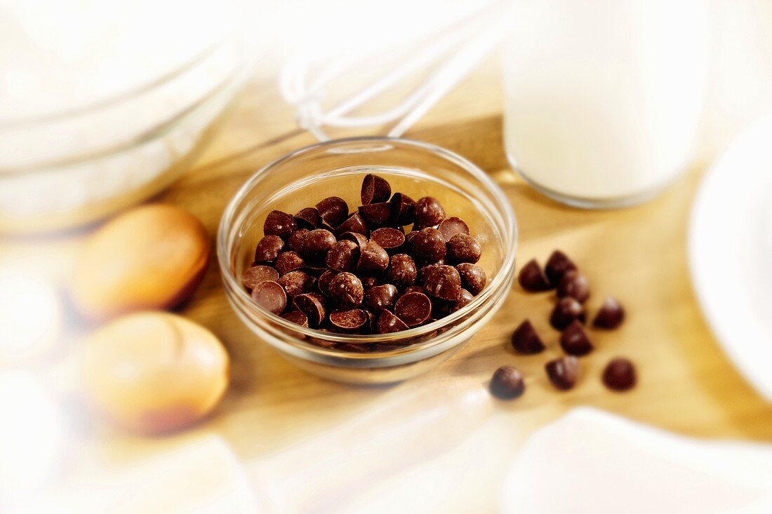 Chocolate chips in a dish surrounded by baking ingredients