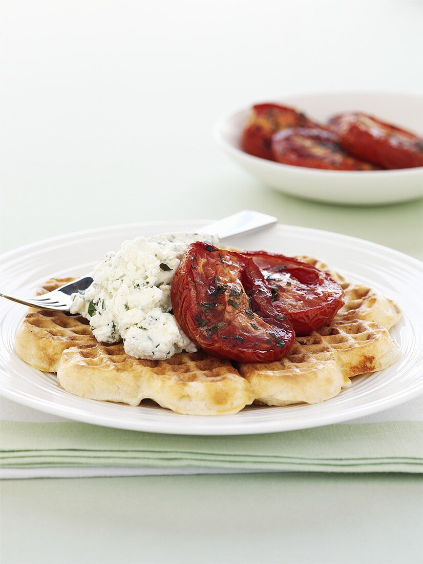 Savoury waffles topped with soft cheese and baked tomatoes