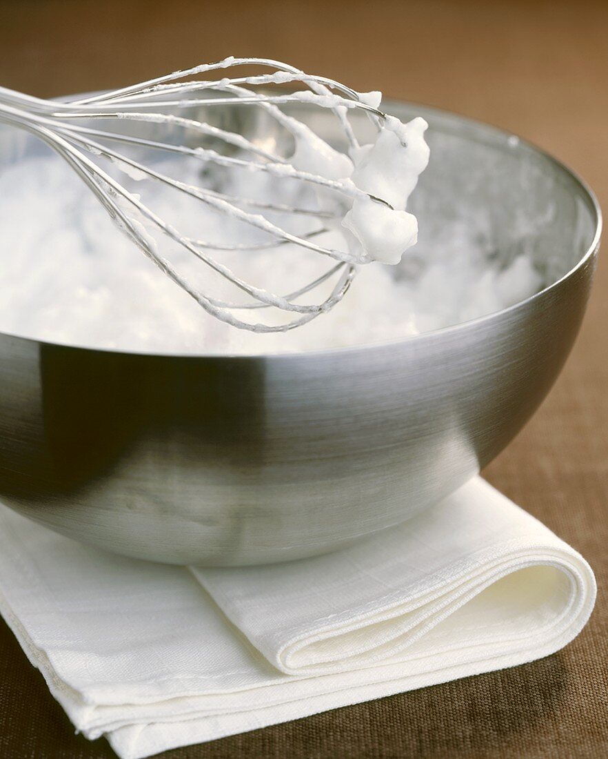 Beaten egg white in bowl with whisk