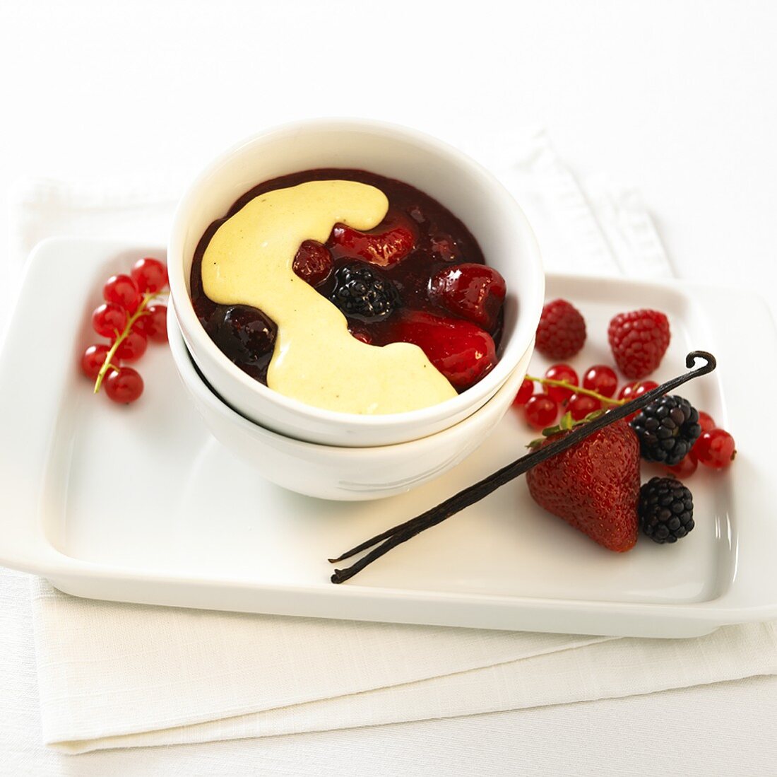 Red fruit compote with custard in a small bowl