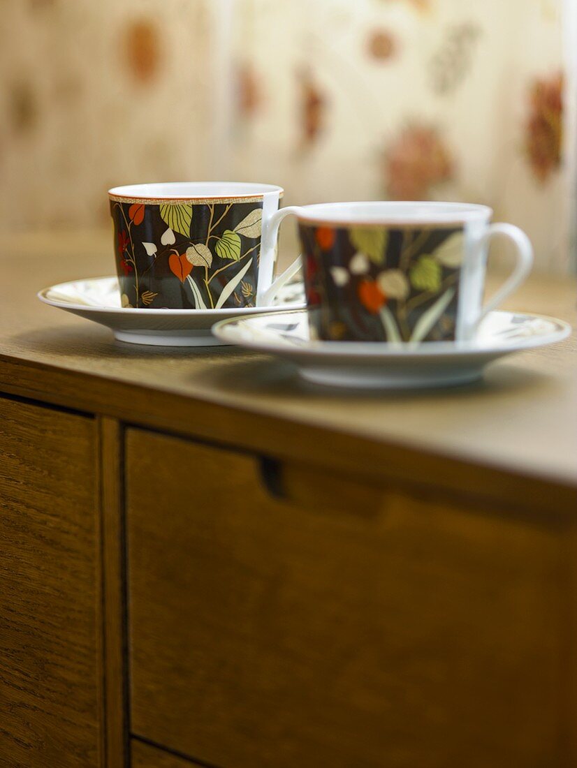 Two cups and saucers on a sideboard