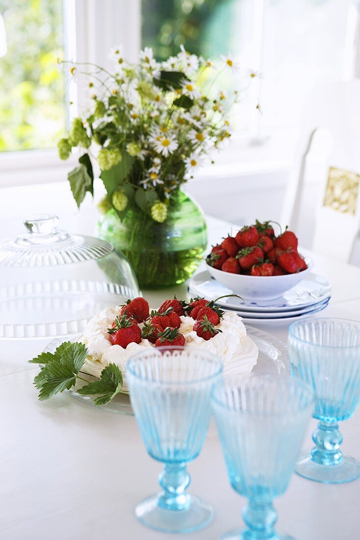 Erdbeerkuchen und Schälchen mit Erdbeeren auf einem Tisch