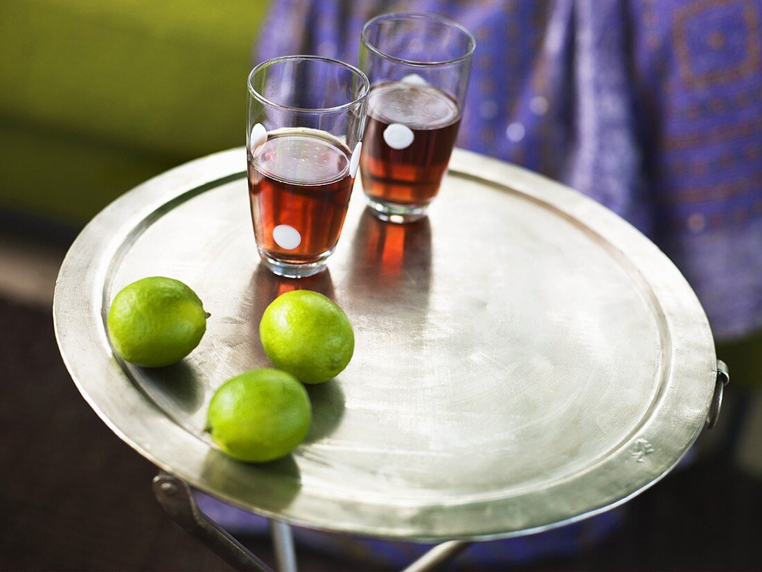 Two drinks and limes on a tray