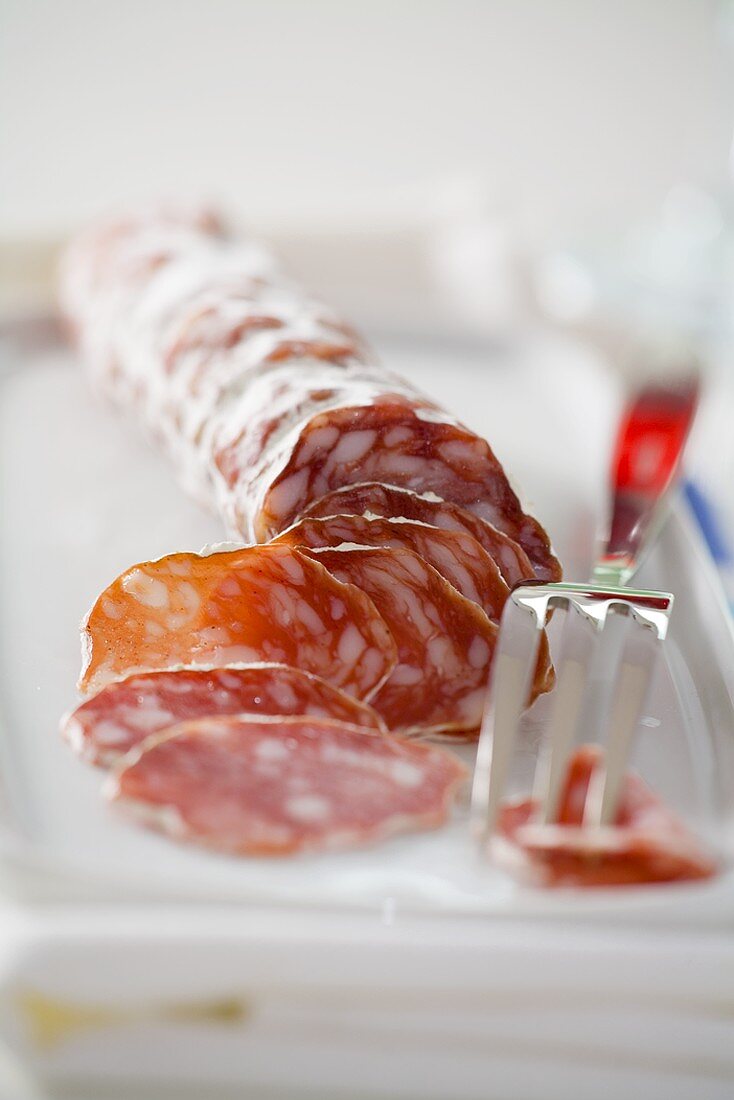 Angeschnittene französische Salami mit Gabel