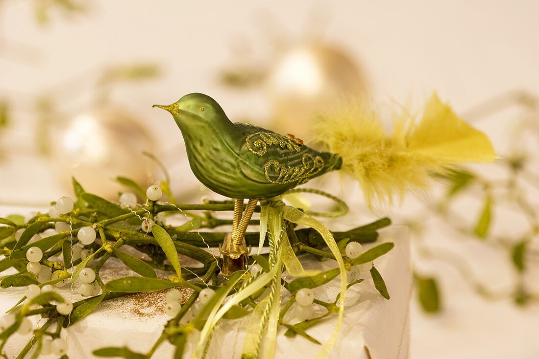 Green glass bird on a parcel decorated with mistletoe