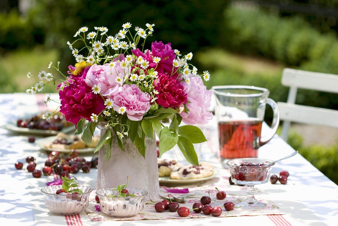 Cherry desserts and vase of flowers on table in garden