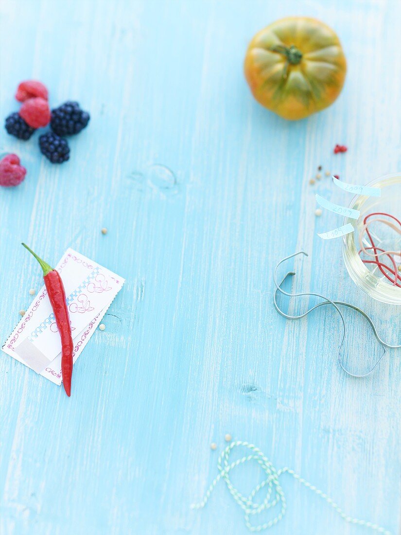 A chili, berries, a beef steak tomato and rubber bands on a wooden surface