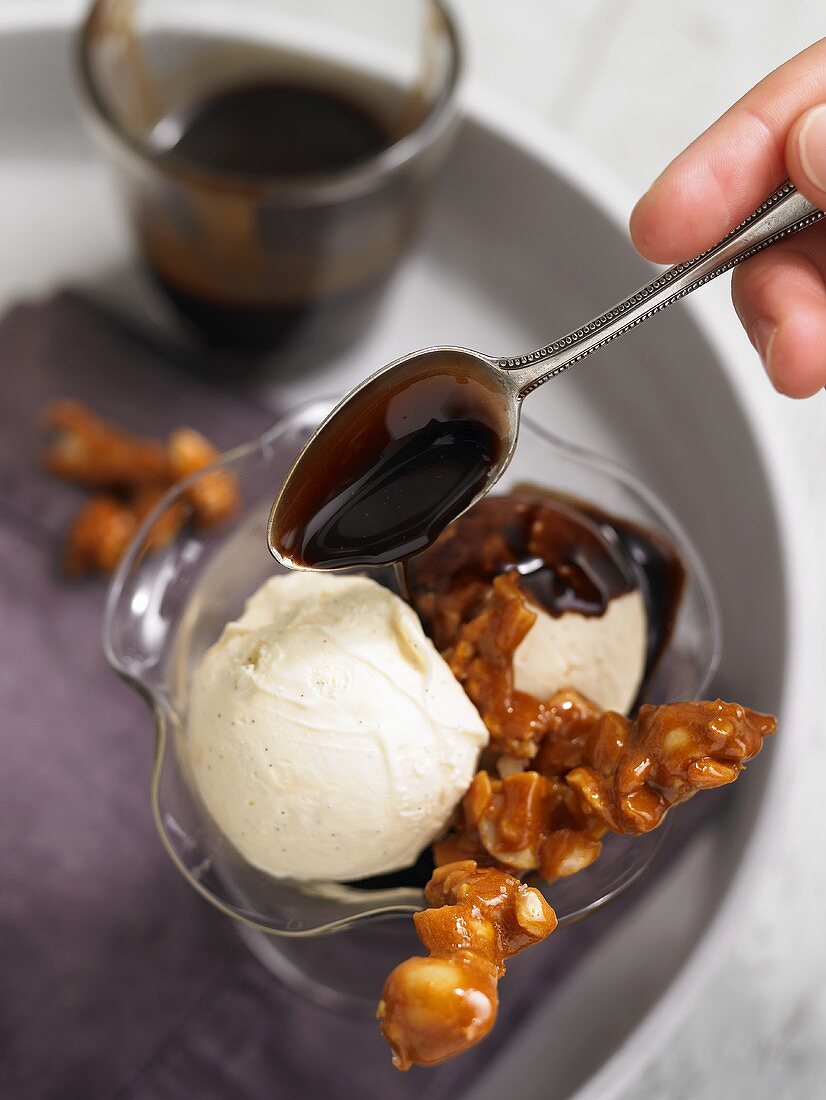 Drizzling chocolate sauce over orange sorbet with macadamia nut brittle