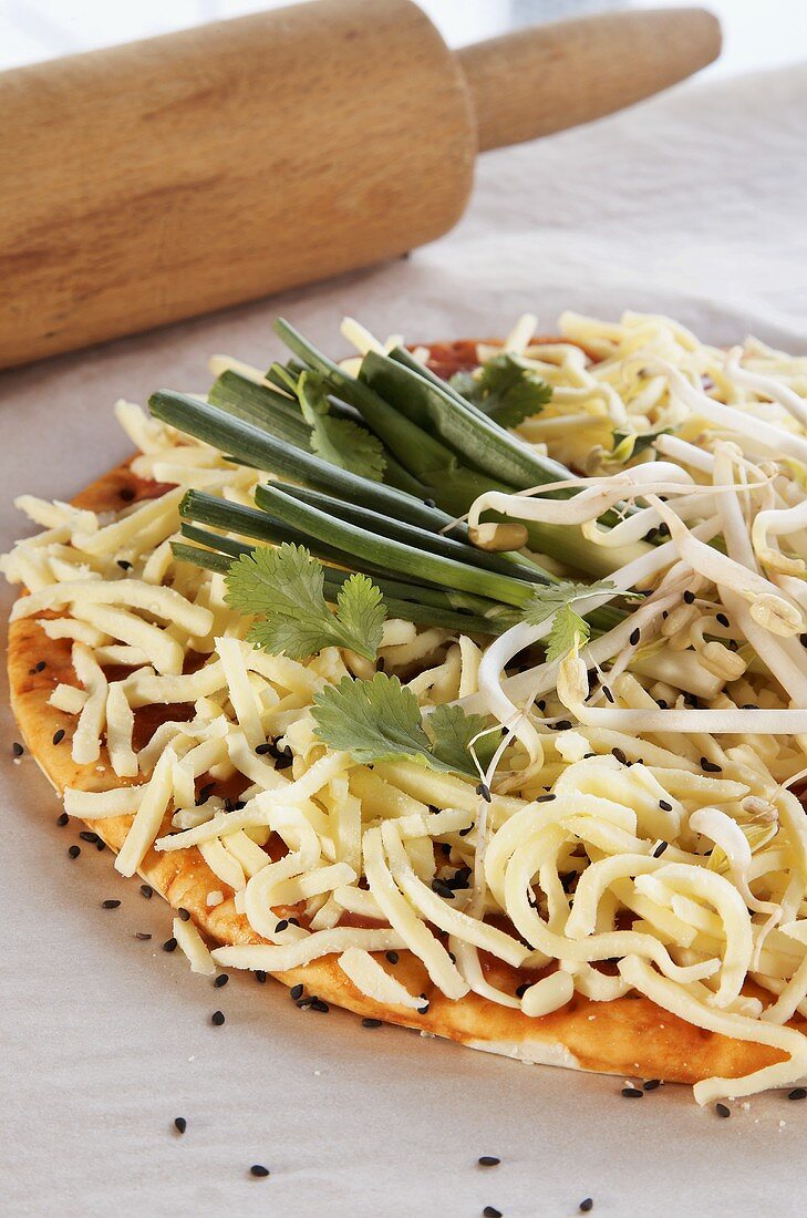 Pizza mit Käse, Frühlingszwiebeln und Sprossen belegt (ungebacken)