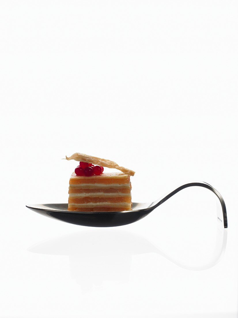 A layered blini cake on a curved spoon (molecular gastronomy)