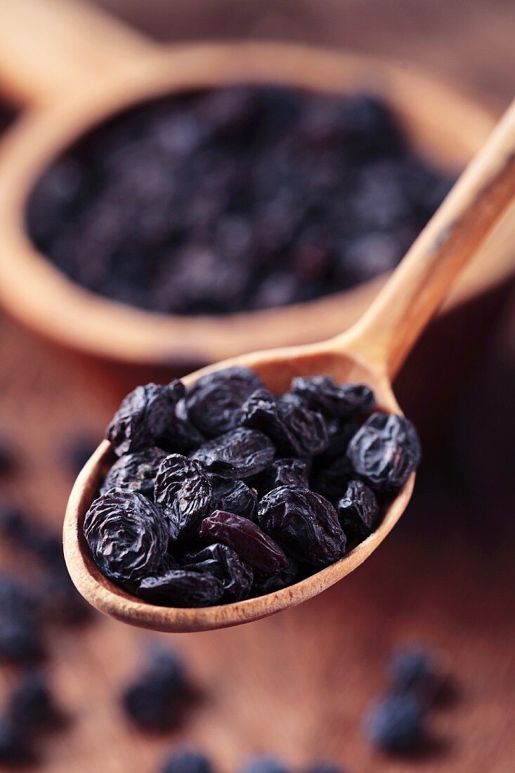 Black raisins on a wooden spoon