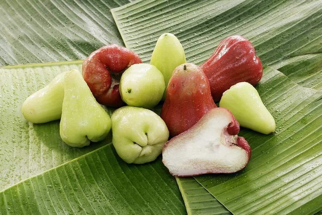 Red and green Java apples on banana leaves