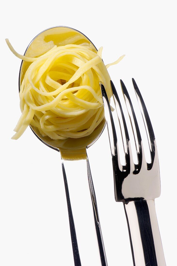 Cooked taglierini on spoon with fork